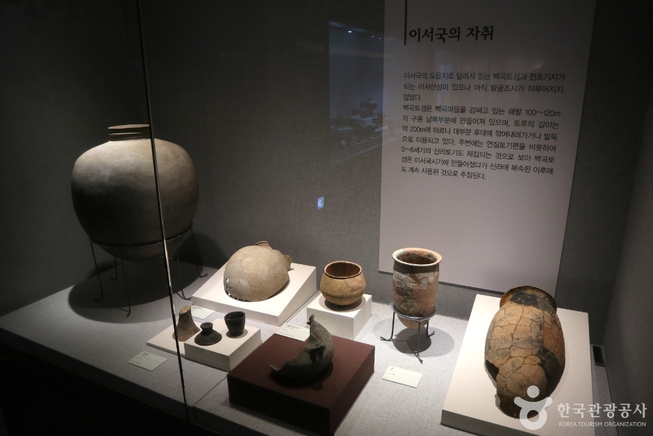 조명 아래 진열장 속 토기들과 설명 패널